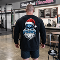 Apocalypse Gym Wear frozen Santa skull long sleeve black gym shirt worn by a bodybuilder. Back view showing an icy blue skull graphic with red Santa hat and frosted dripping typography.