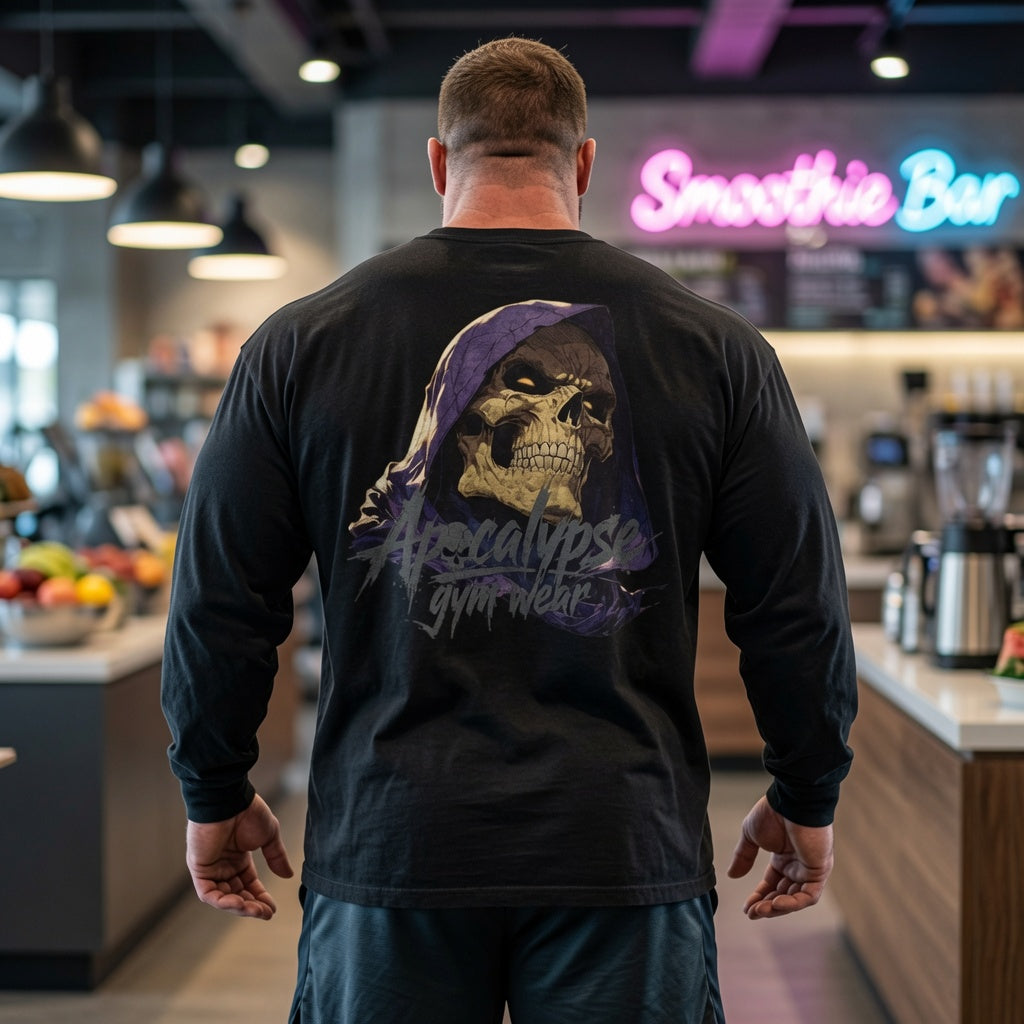 Apocalypse Gym Wear hooded skull long sleeve black shirt back view worn by a bodybuilder in a gym, showing a hooded skull graphic with purple cowl and slate-grey brand logo.