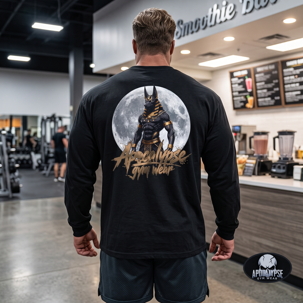 Apocalypse Gym Wear Anubis black long sleeve shirt back view worn by Ryan in a gym, featuring a full moon Anubis back graphic with metallic gold typography.