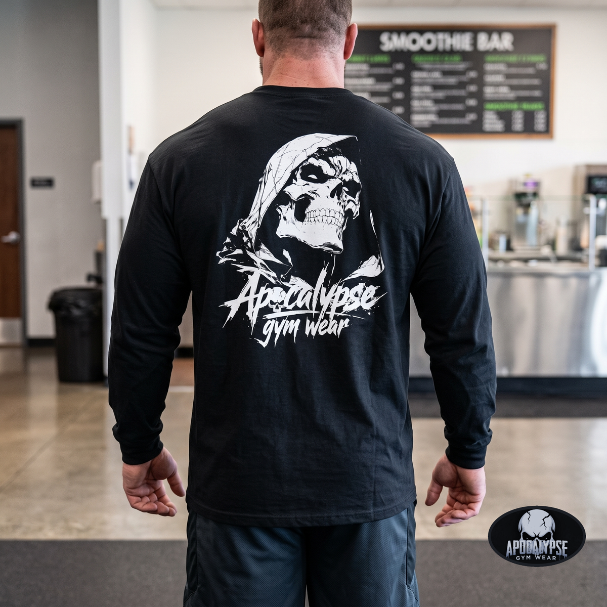 Model Lifestyle Back View: Rear view of male fitness model inside a gym showcasing the large white hooded skull graphic across the back of the black long sleeve pump cover.