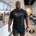 Apocalypse Gym Wear front logo black t-shirt worn by a bodybuilder. Front view showing dark grey splatter brush brand typography print across the chest.