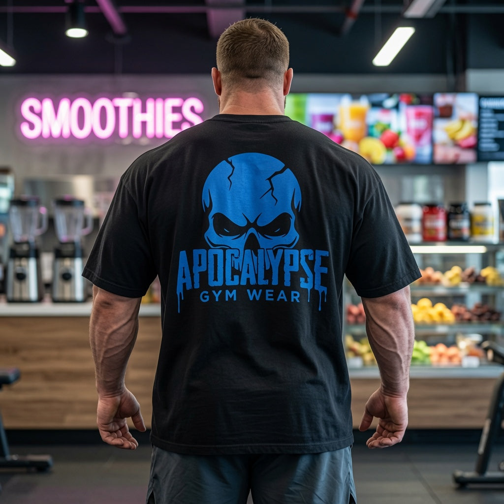 Apocalypse Gym Wear, Large, ink-heavy brand crest logo featuring a dark, mythic skull design with deep cross-hatching and fine linework textures, printed in high-contrast monochrome on the back of a vintage black, boxy heavyweight cotton t-shirt.